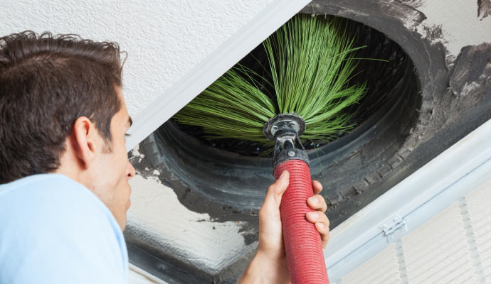 Person cleaning air duct waste with equipment