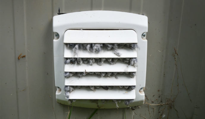 Vent on an exterior wall clogged with lint and debris