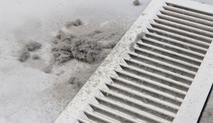 A dirty air vent with significant dust and debris