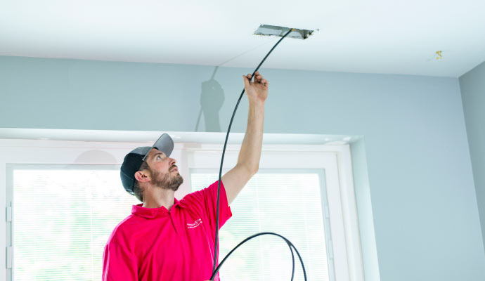 Person cleaning air duct with equipment