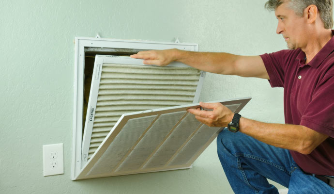 A person replacing a dirty air filter