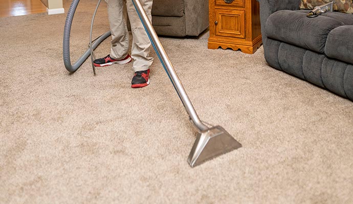 person cleaning beige carpet with vaccume cleaner