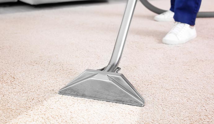 A person cleaning carpet using hot water extraction method