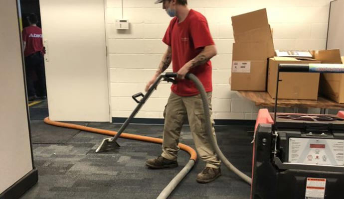 A person cleaning a carpeted floor using a machine