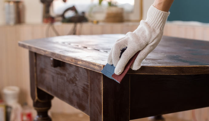 Person cleaning wooden table with equipment