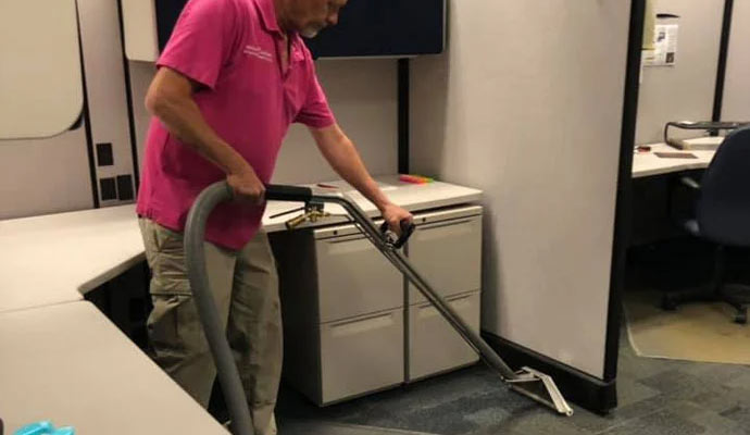 Person cleaning office carpet with a vacuum cleaner