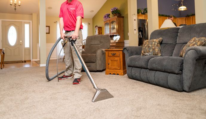 A person cleaning a carpet in the living room with equipment