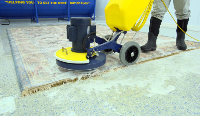 A person cleaning a rug with a cleaning machine