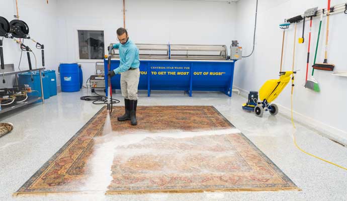 A person cleaning a large rug in a professional facility