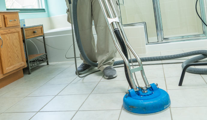 Person cleaning tile floor with equipment