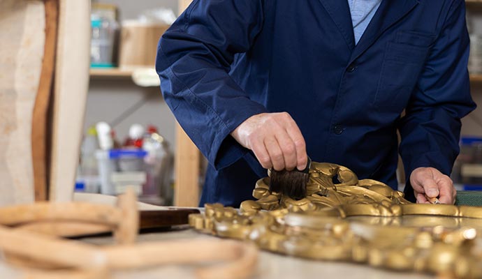 Person cleaning an antique piece